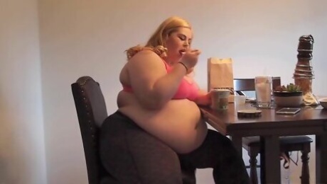Blonde plumper rubs her belly while eating ice cream